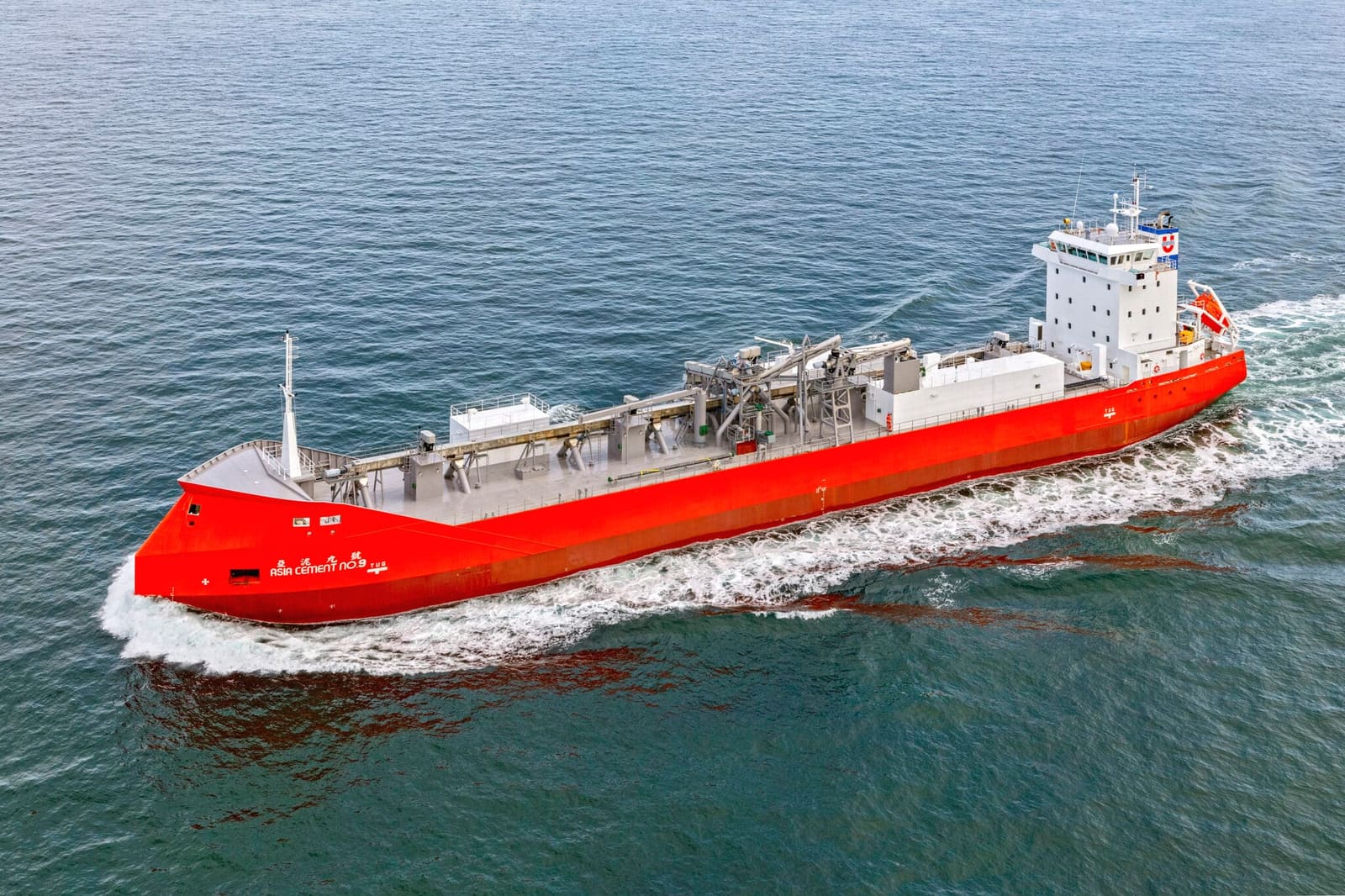 Asia Cement No. 9 self-discharging cement carrier for Yang Ming Marine Transport, red hull underway at sea, aerial view.
