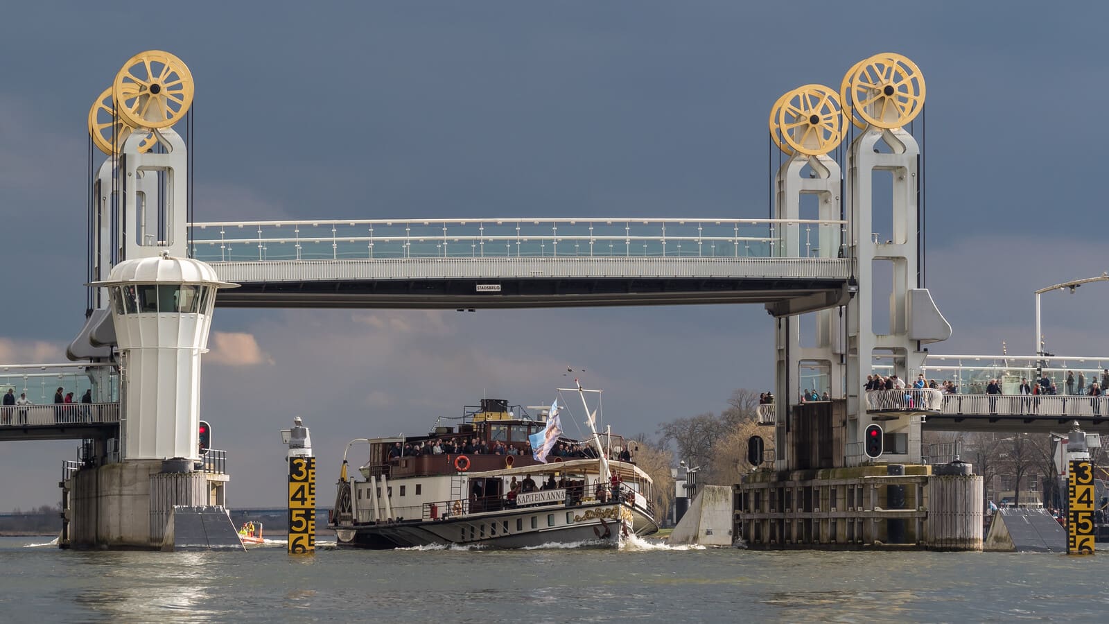 Vertical-lift Stadsbrug at Kampen with raised deck and a historic passenger boat passing underneath, one of three automated bridges commissioned by Black Frog Elektro for Sissing Nord.