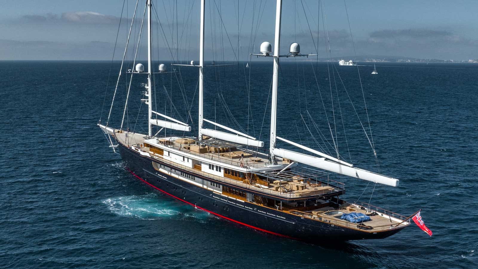 Koru 127-metre three-masted sailing superyacht built by Oceanco, navy hull with teak deck at sea.