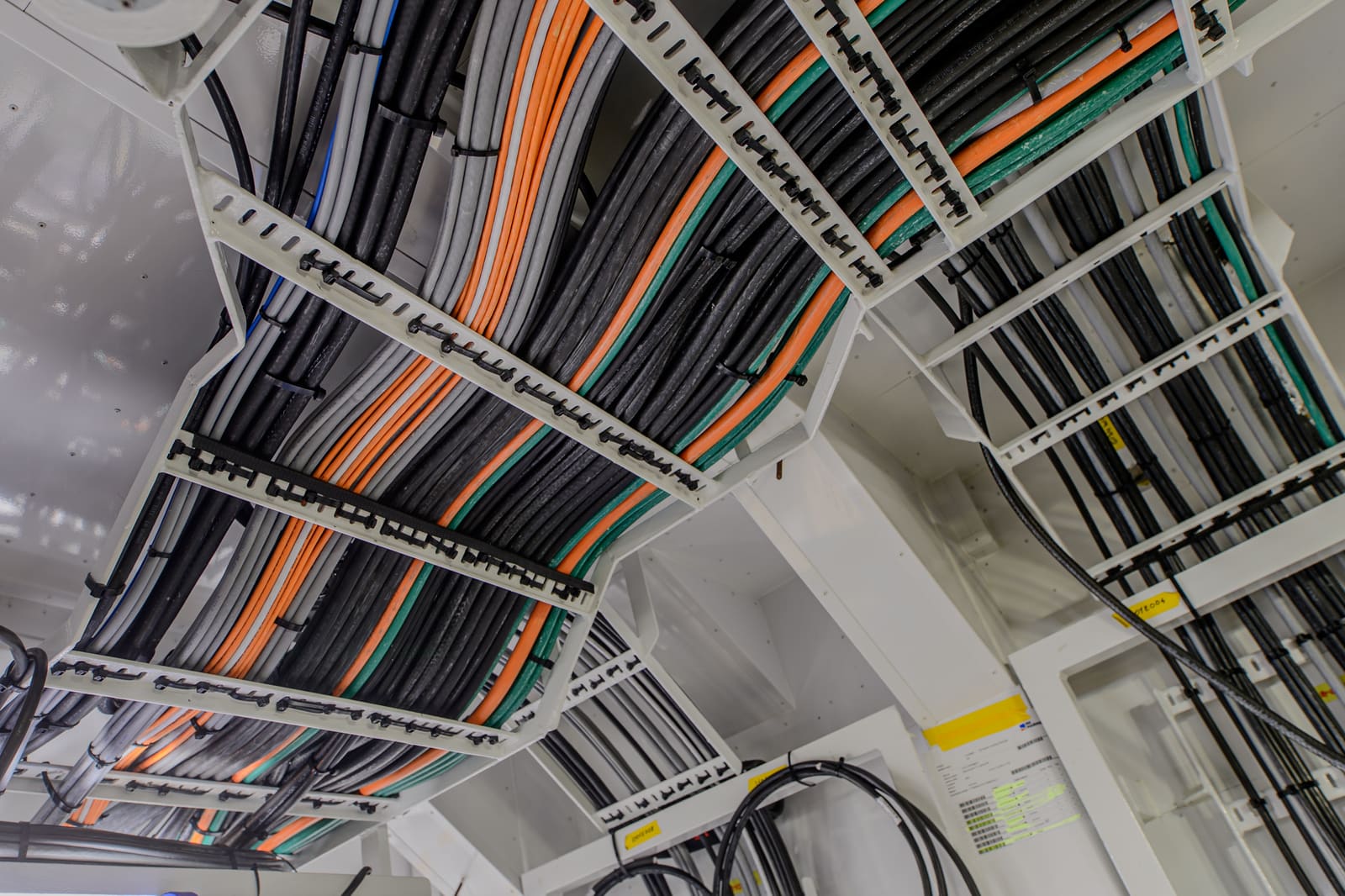 Cable tray junction with marine power cables turning between perpendicular trays inside a ship compartment