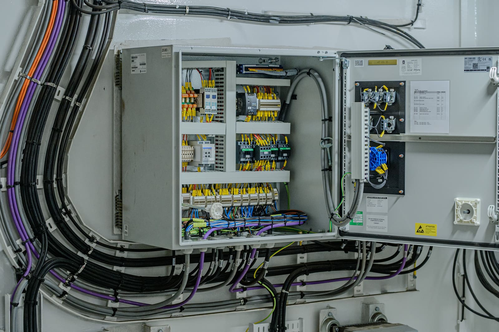 Open marshalling cabinet with terminated marine cables radiating out into the surrounding cable tray network