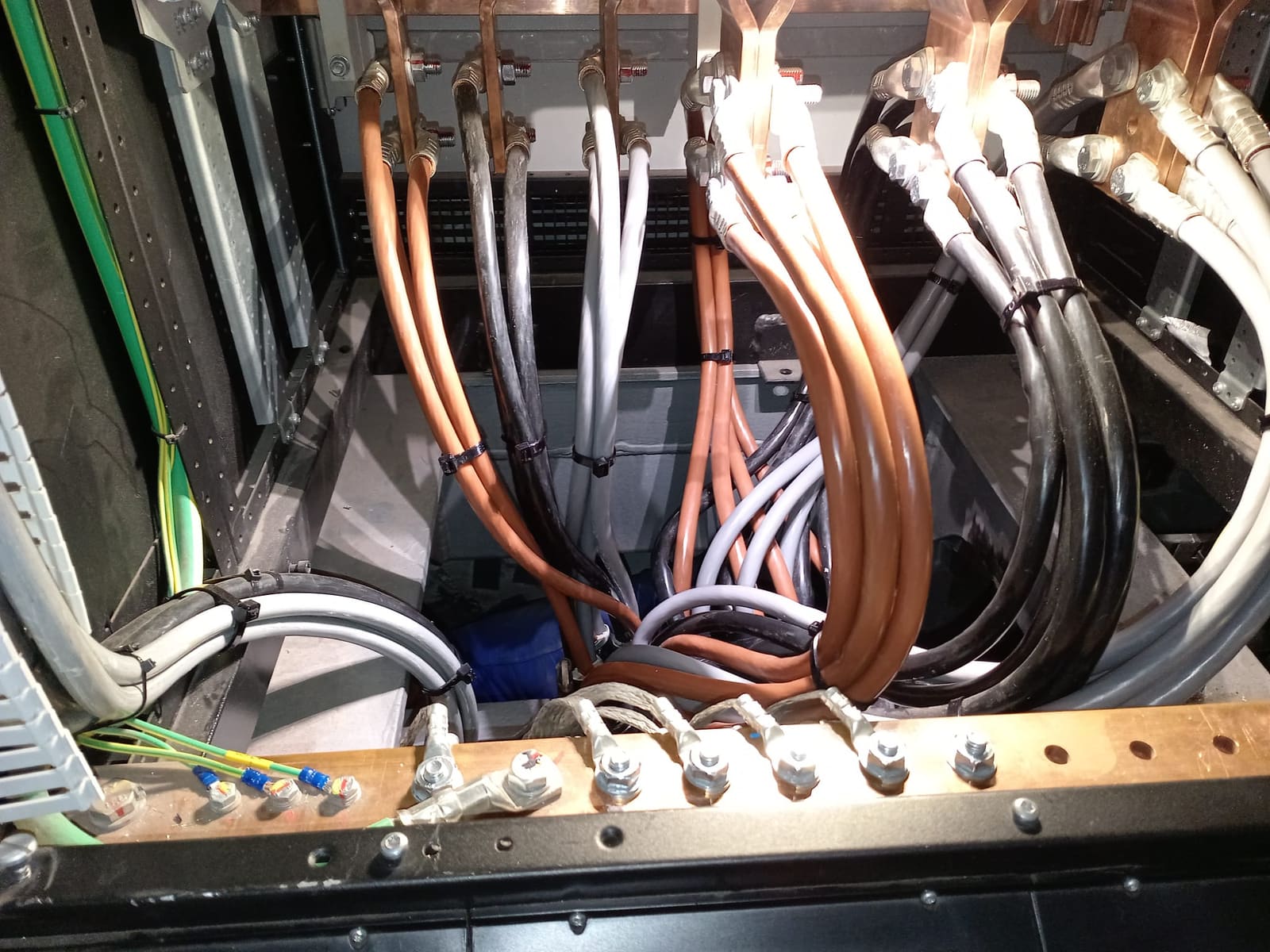 Marine switchboard busbar termination with copper lugs bolted to the bus and brown, grey and black single-core cables fanned in