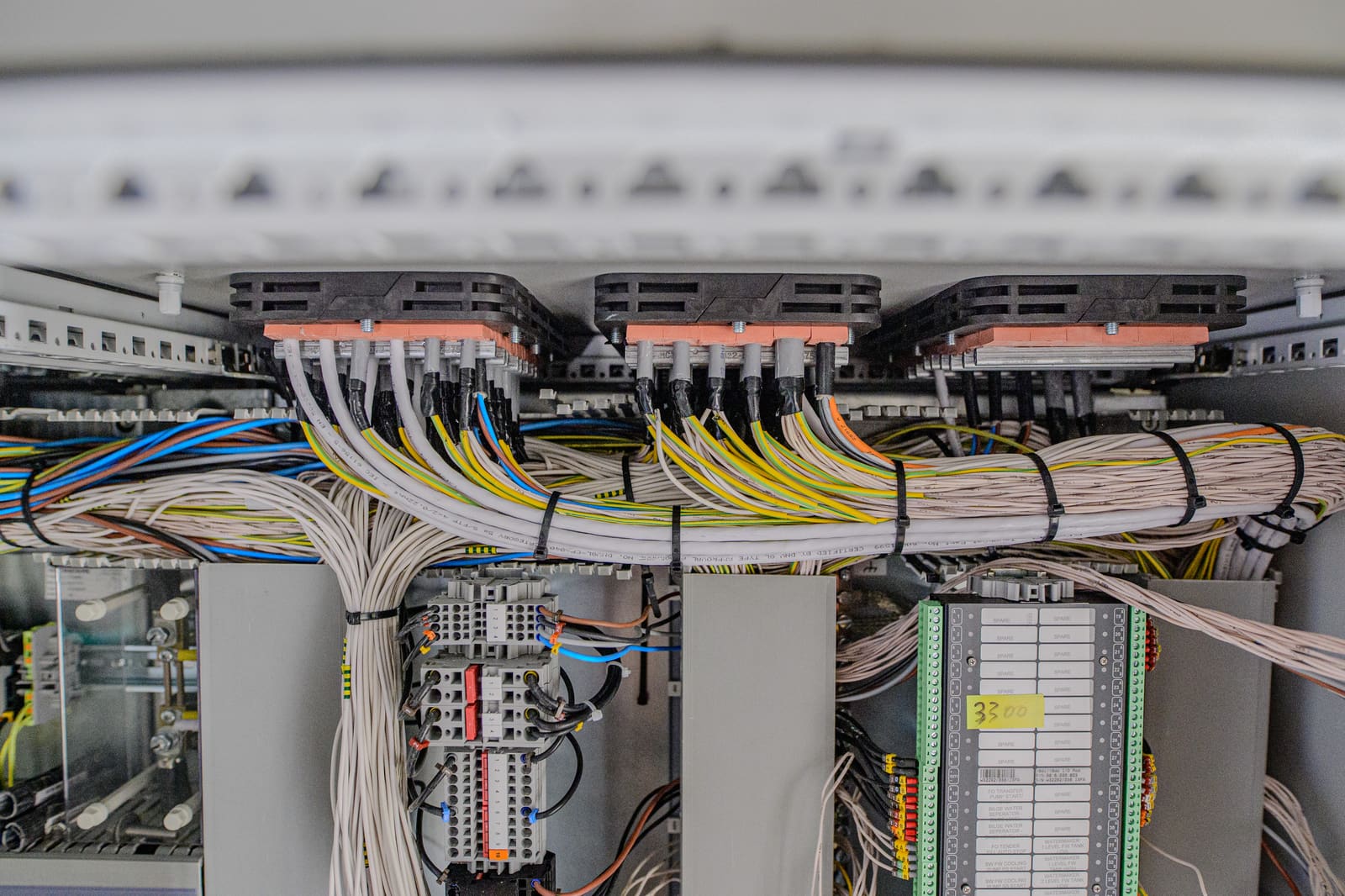 PLC panel internal wiring with multicore cables fanned out from spring-clamp terminal blocks to digital I/O modules below