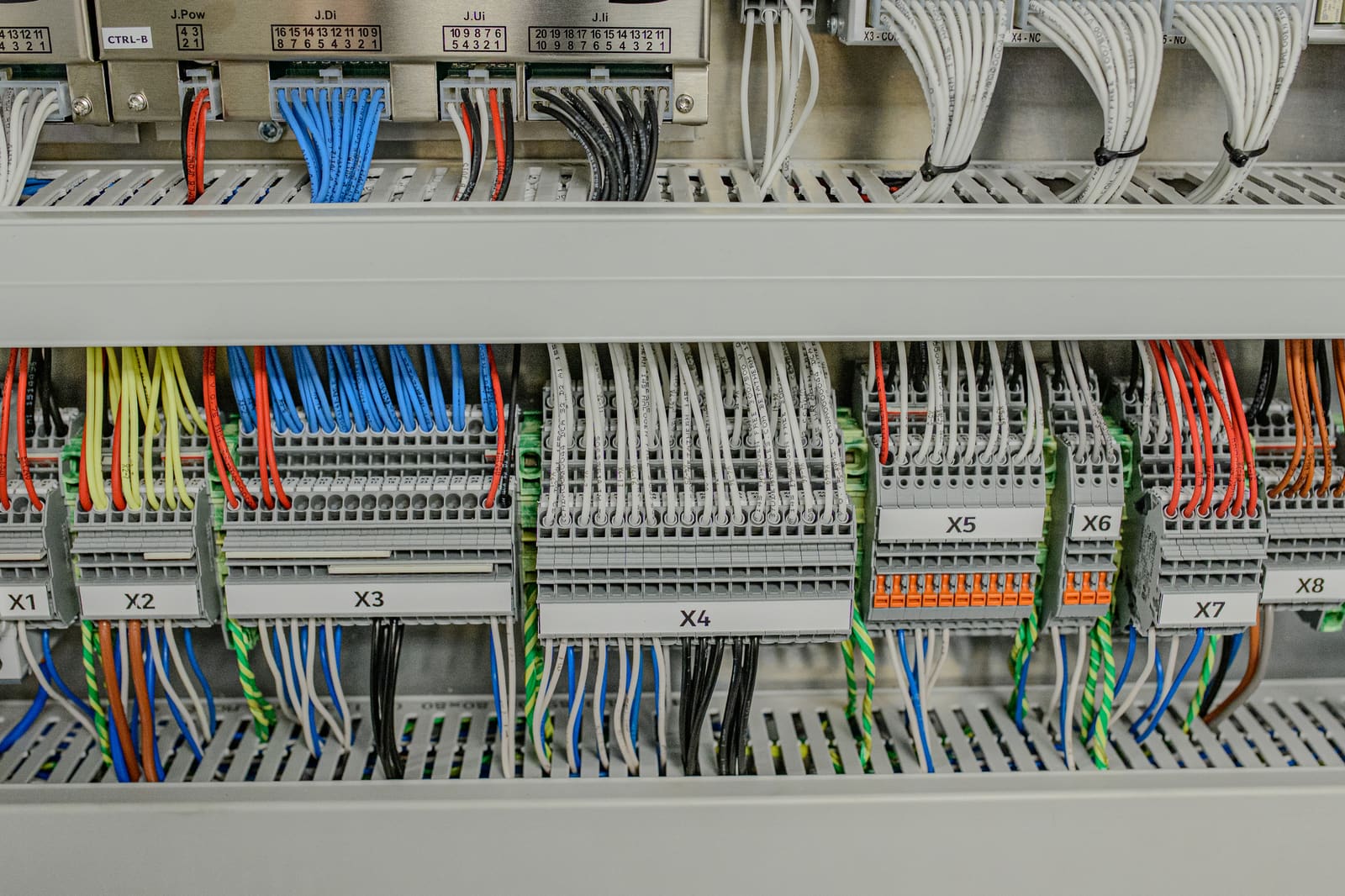 Numbered terminal strip array X1–X8 in a marine control cabinet with neatly dressed signal cables terminated on both sides