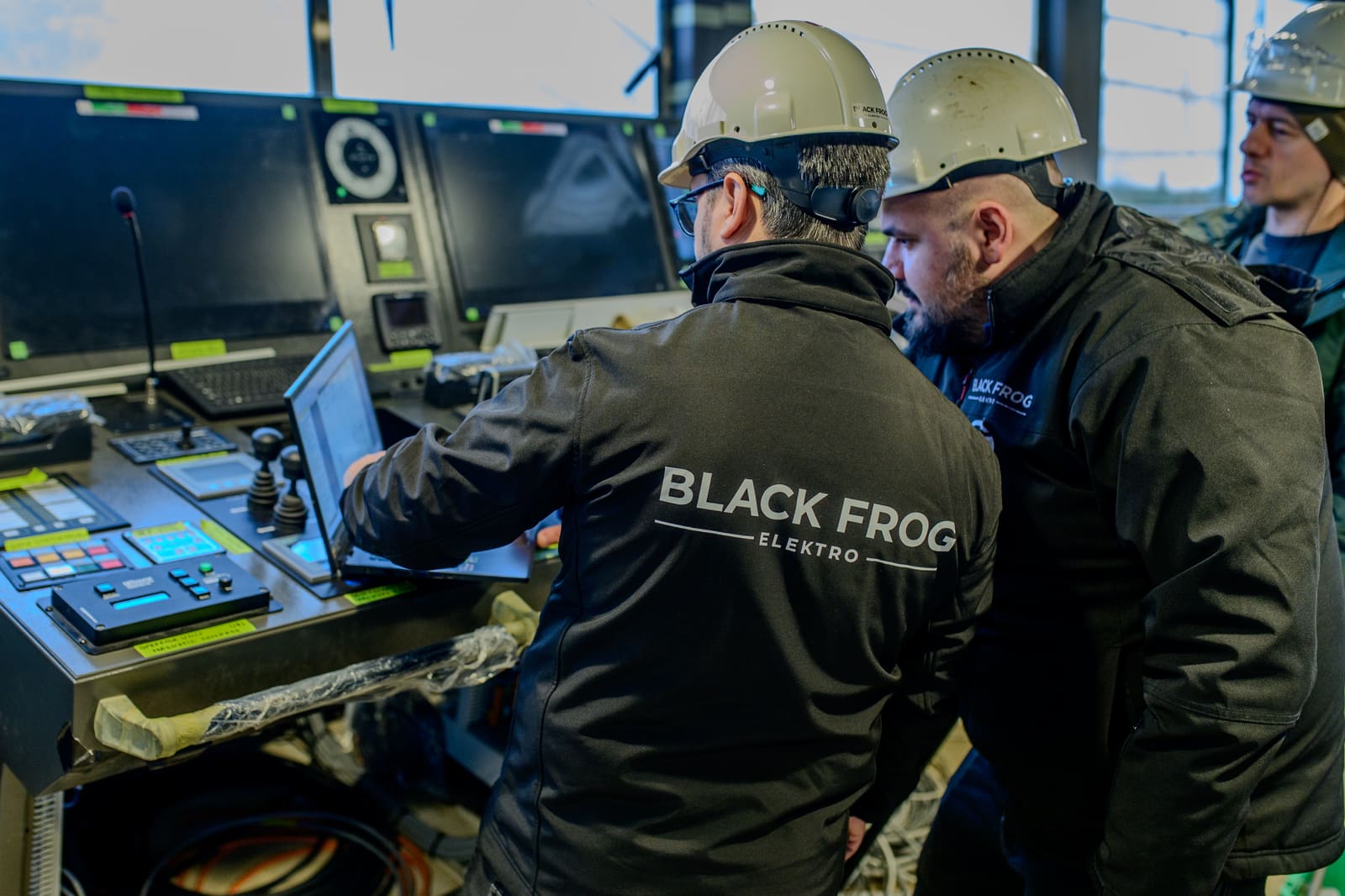 Two Black Frog Elektro engineers checking thruster control feedback on a tug bridge console during commissioning