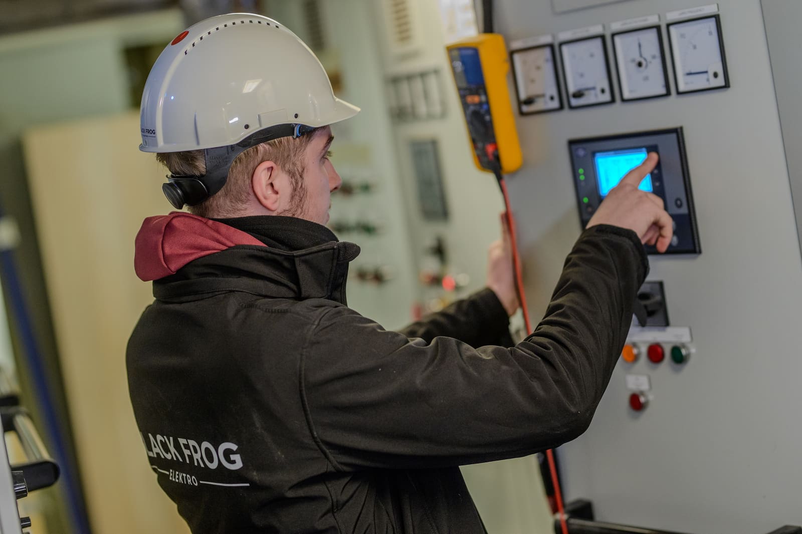 Black Frog Elektro engineer operating an HMI panel during functional testing of a marine switchboard.