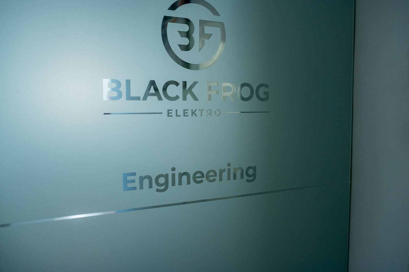 Frosted glass door branded "Black Frog Elektro — Engineering" at the design department entrance