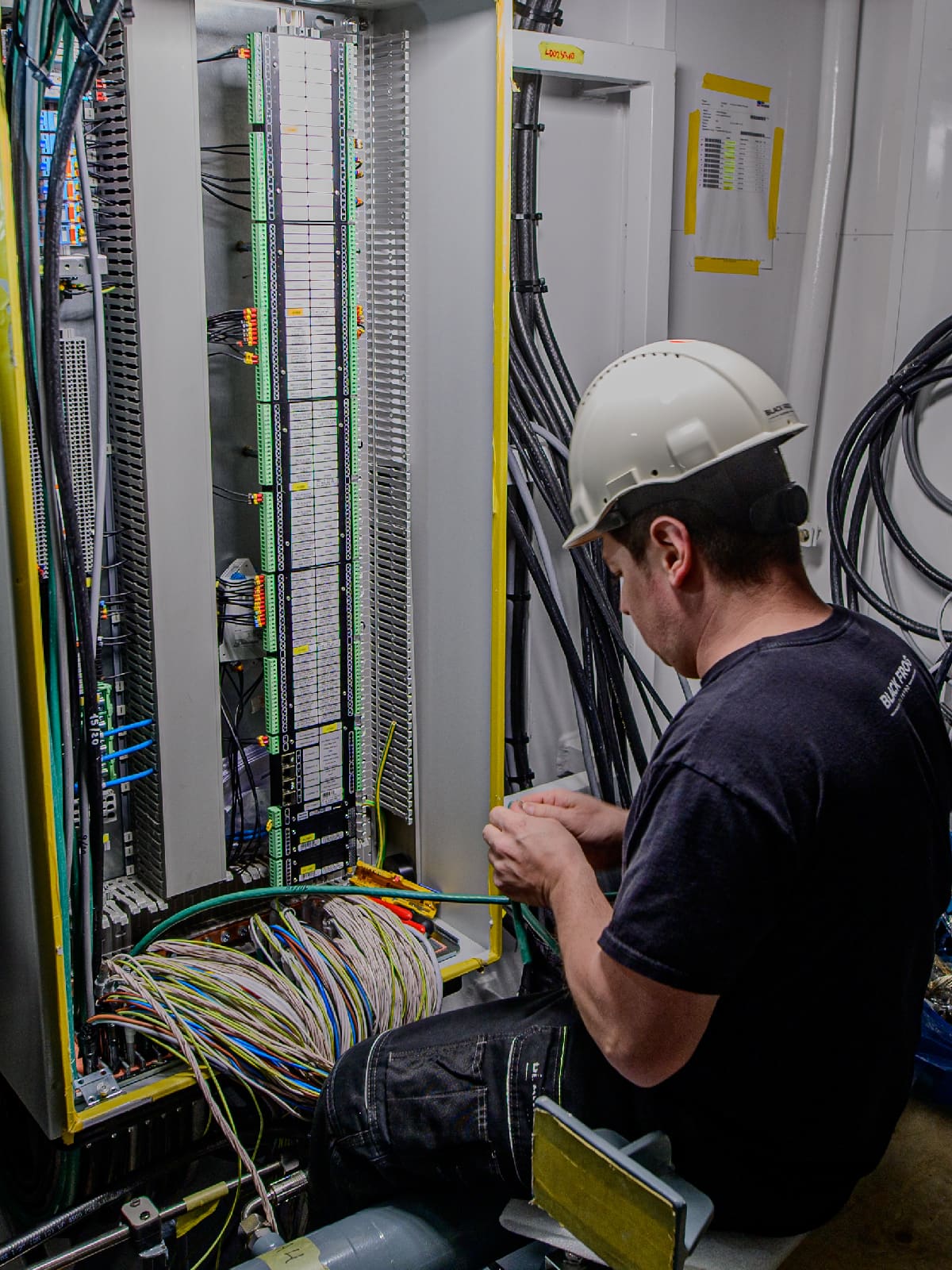 Close-up of a technician wiring an electrical connection inside a switchboard.