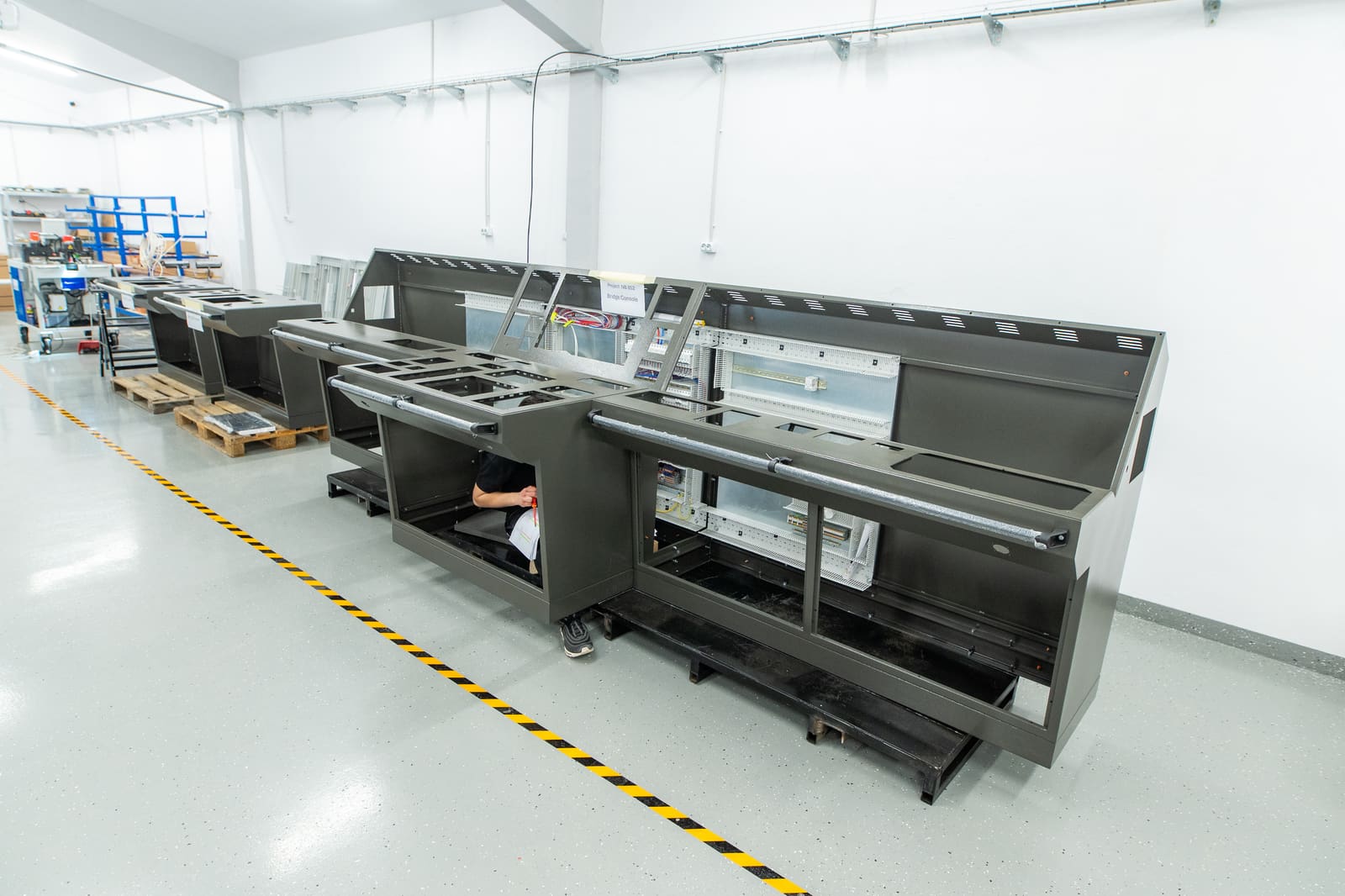 Row of bridge consoles in progress on the Black Frog Elektro panel-building shop floor with safety walkway marked in yellow-black