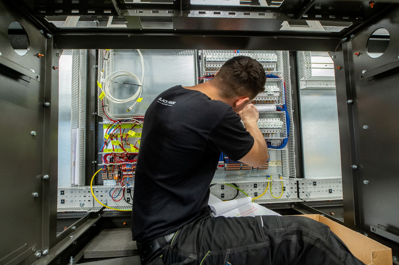 Black Frog Elektro panel builder fitting wireways and DIN rails inside a marine control cabinet at the workshop