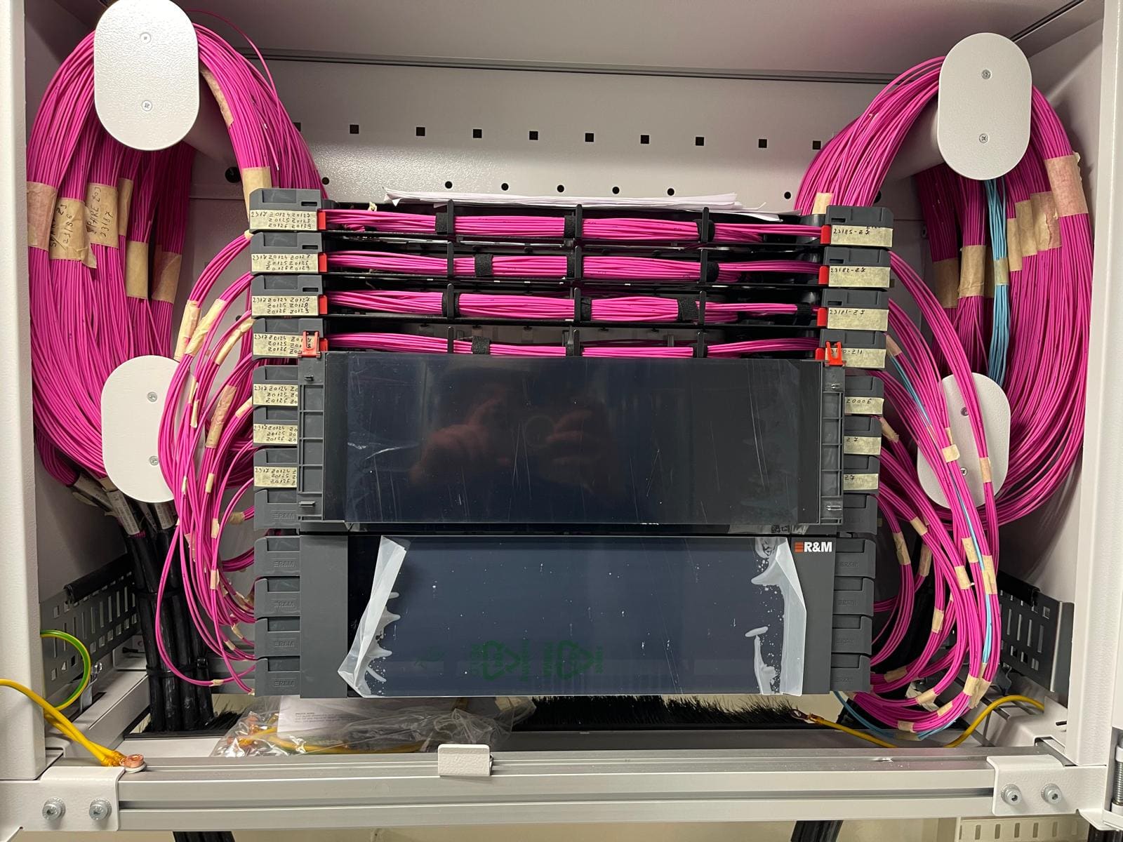 Marine fiber optic patch cabinet detail with magenta patch cords landed on stacked patch panel shelves