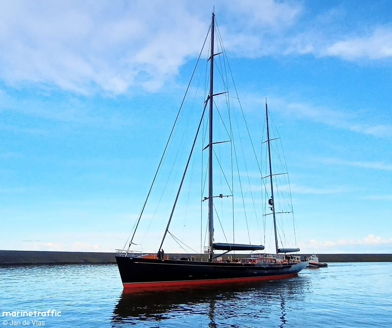 60-metre two-masted sailing yacht Maximus built by Vitters Shipyard in Zwartsluis, black hull with red waterline, sails furled in a calm harbor.