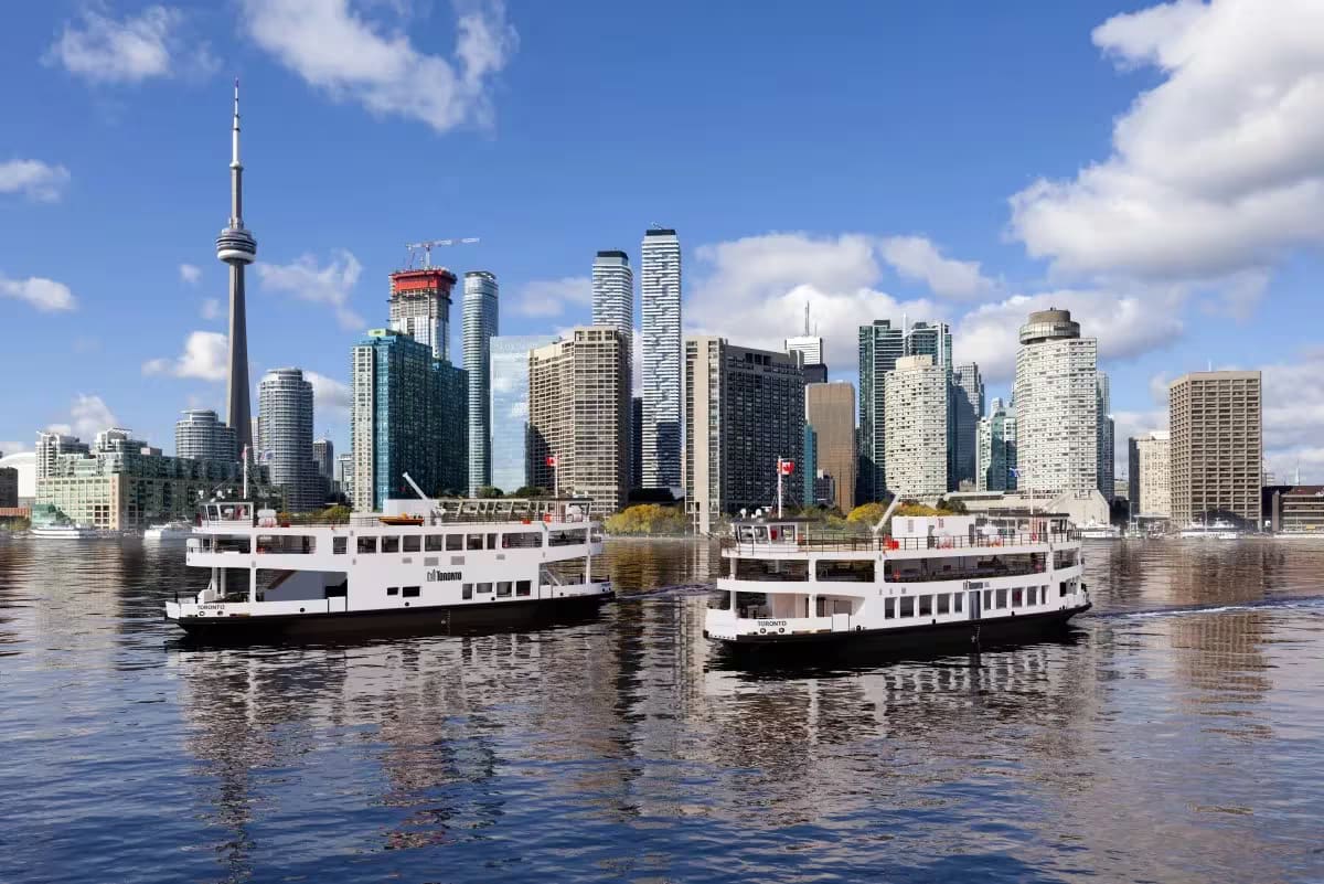 Two Damen 5013 hybrid passenger ferries for the City of Toronto with downtown Toronto skyline and CN Tower in the background.