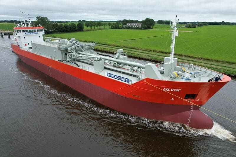 Cement carrier Ulvik for SMT Shipping transiting a Dutch canal, red hull with Royal Bodewes superstructure lettering.
